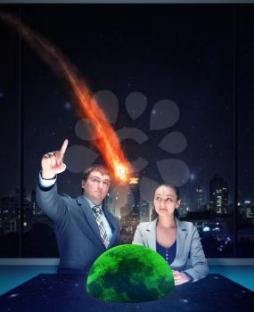 Businessman and businesswoman looking at the meteorite falling on the earth model