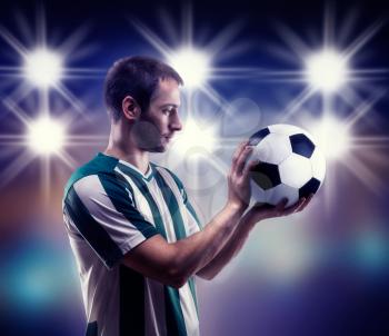 Football-player holding a ball over black background