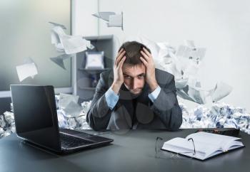 Frustrated businessman holding his head sits in the office