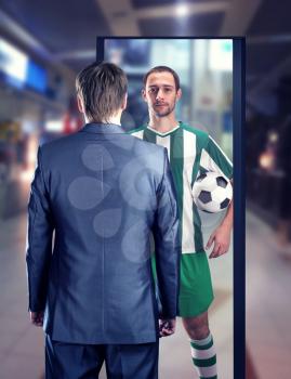 Businessman dreaming to be a football-player stands in front of the mirror