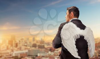 Businessman with angel wings on his back looking at the city