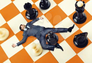 Businessman lying on the chess board
