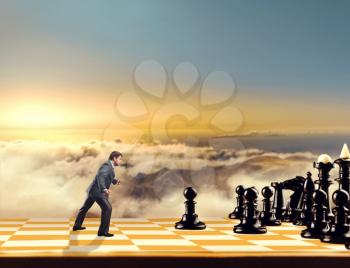 Businessman on the chess board fighting with black chess team in the sky