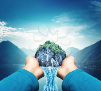 Male hands holding waterfall over moutains landscape with lake