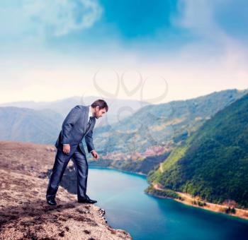 Businessman standing on the mountain edge above the river