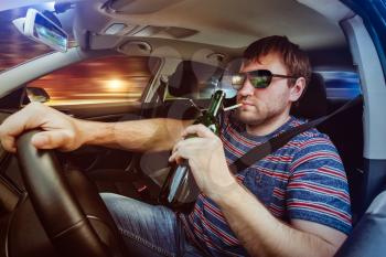 Man driving the car, drinking wine and smoking