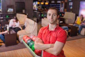 Portrait of man standing in bowling with crossed hands
