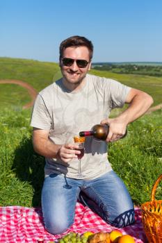 Smiling man pouring out wine on the picnic