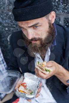 Sad homeless is having his meal closeup