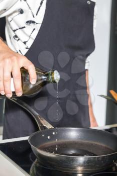 Close up of man's hand pouring oil in the pan