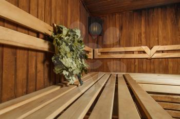 Sauna for relaxation and wellness, broom on the wooden bench.