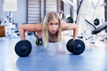 Young girl doing push-ups with dumbbells