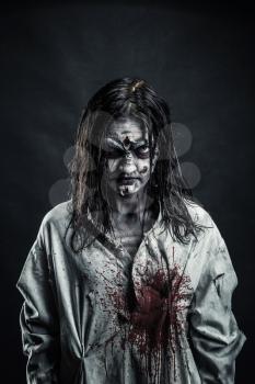 Portrait of the horror zombie woman with bloody face against the black background