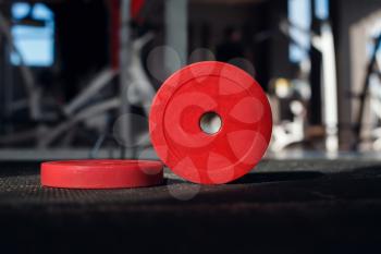 Red weight plates on the floor in the gym