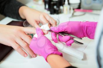 Manicure specialist in rubber gloves care by finger nail in spa beauty salon. Manicurist uses professional manicure tool. Manicure service.