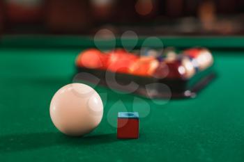 White ball and chalk on the green cloth of the billiard table.