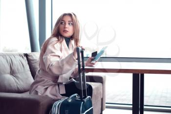 Beautiful woman sitting on the couch in front of the window in an airport hall