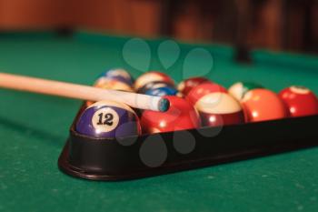 Billiard balls in triangle near by cue on the pool table.