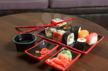 Japanese traditional seafood. Japan food on wooden background. Sushi set with rice rolls, salmon fish, sauce, wasabi and ginger.
