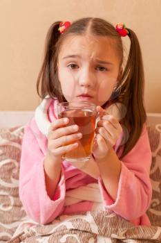 Sick little girl has drink hot tea.