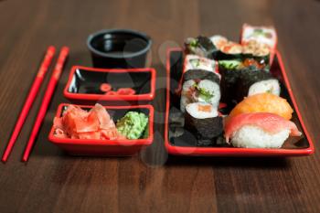 Japanese traditional seafood. Japan food on wooden background. Sushi set with rice rolls, salmon fish, sauce, wasabi and ginger.