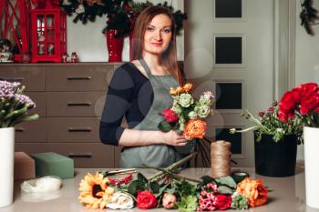 Female florist working with flowers while she made decorative bouquet