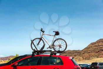 Car is transporting bicycle on the roof. Bike on the trunk.