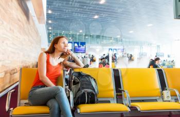 Young woman sitting on the chair in a station hall. Suitable for bus, railway, metro station or airport.