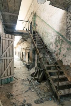 Old prison corridor with grunge wooden staircase and doors.