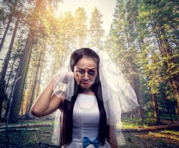 Bride with tearful face, pine forest on background. Unhappy marriage