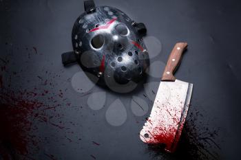 Serial murderer tools isolated on black background. Bloody meat cleaver and hockey mask
