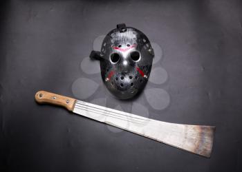 Murderer hockey mask with bloody stripes and machete isolated on black.  Serial maniac instruments
