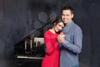 Beautiful young loving couple embraces,retro piano on background