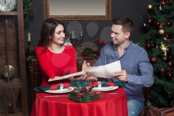 Young smiling couple explore the menu at luxury restaurant. Romantic date, man and woman in love