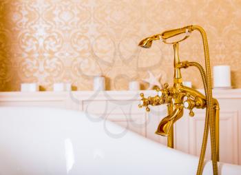 Rich gold faucet and white bath in the bathroom. Luxury sanitary equipment
