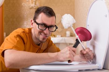 Man in glasses cleaning the toilet bowl. Luxury bathroom interior on background