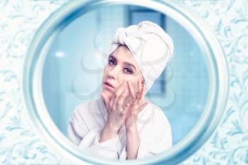 Beautiful woman take care of her face against mirror in bathroom