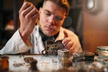 Watchmaker oil lubricates the mechanism of the old clock. Mechanical watch repairing