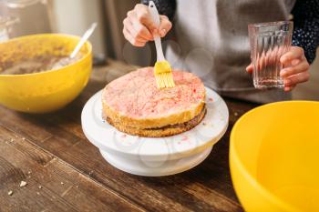 Woman cook hands smears filling for cake. Tasty dessert homemade cooking
