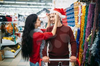 Couple buying christmas decorations in store, family tradition. December shopping of new year holiday goods