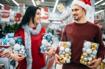 Happy couple holds boxes with Christmas toys in shop, family tradition. December shopping of holiday goods and decorations