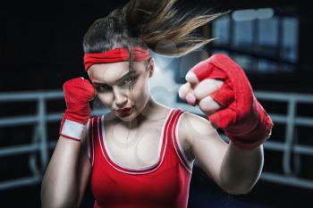 Female boxer in red gloves and sportswear training in gym, boxing workout