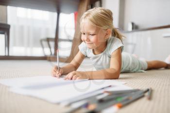 Little girl draw lying on the floor at home. A truly carefree childhood, happy time