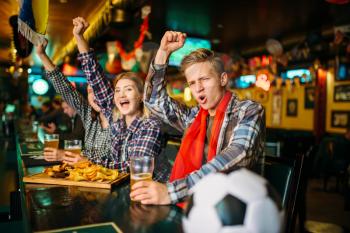 Young football fans celebrate the victory of their favorite team at the counter in sports bar. Tv broadcasting, teenager watching the match, success game celebration in pub