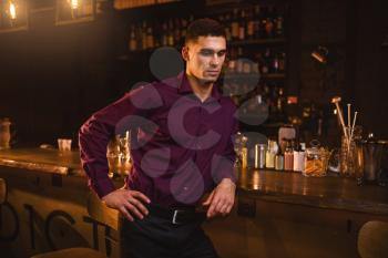 Young elegant man in shirt standing at the bar counter. Night lifestyle, businessman leisure in nightclub