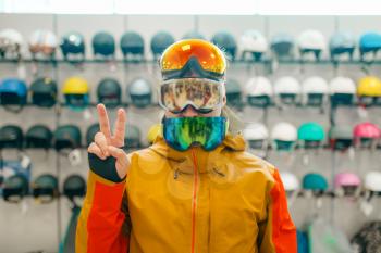 Man at the showcase trying on three masks for ski or snowboarding, front view, shopping in sports shop. Winter season extreme lifestyle, active leisure store, buyers choosing protect equipment