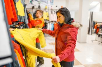 Woman at the showcase choosing skiing or snowboarding equipment, shopping in sports shop. Winter season extreme lifestyle, active leisure store, customer buying ski