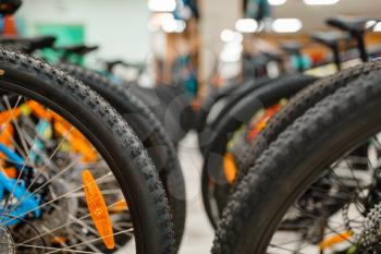 Rows of mountain bicycles in sports shop, focus on wheels, nobody. Summer active leisure, showcase with bikes for extreme riding, cycle sale