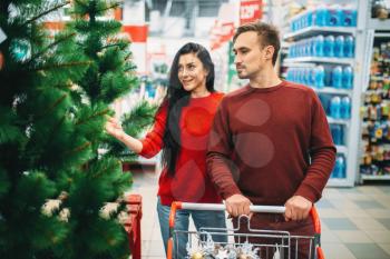 Couple buying new year goods in supermarket. Christmas shopping, choosing of holiday decorations