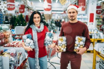 Happy couple holds boxes with Christmas toys in shop, family tradition. December shopping of holiday goods and decorations